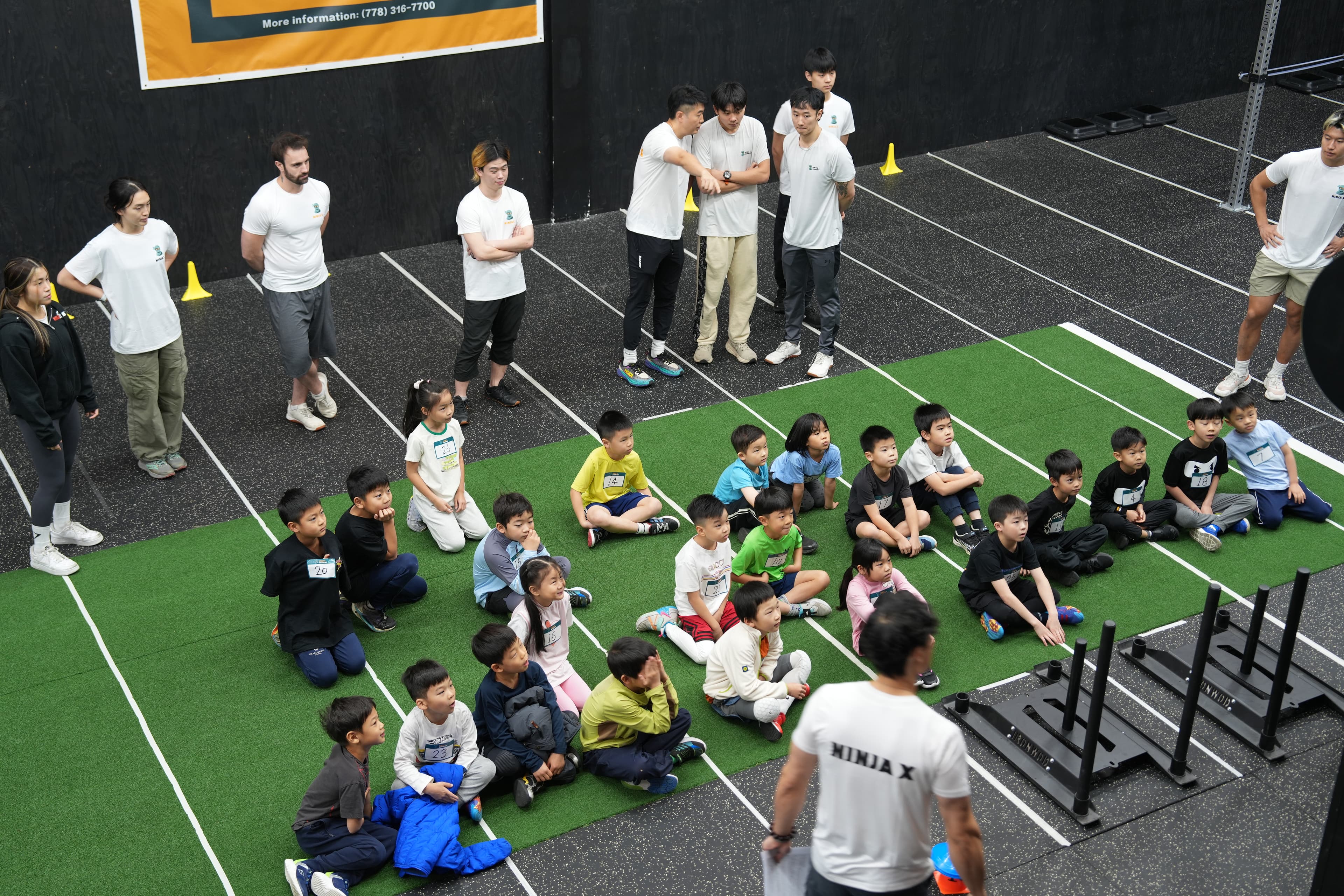A full cohort of Ninja X kids seated on the turf before a session
